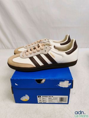 une paire de baskets blanches et marron posée sur une boîte bleue