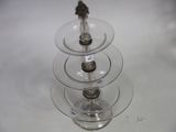 a three tiered glass cake stand with a bird on top