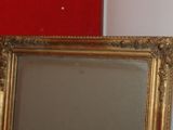 a picture of a gold framed mirror on a red wall