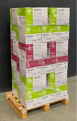 des cartons empilés sur une palette devant un mur noir