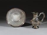 une paire de vases en métal argenté et un bol en métal argenté posés sur un support blanc