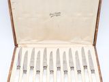 six knives in a wooden case with a white cloth lining
