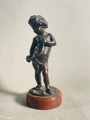 une petite statue représentant un garçon tenant un oiseau, posée sur un socle en bois