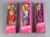 three barbie dolls are in a pink box on a table