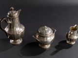 three silver teapots and a coffee pot on a table