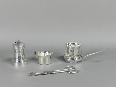 trois objets en argent posés sur une table, à côté d'une paire de ciseaux
