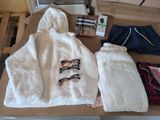 un tas de vêtements posé sur une table, sur laquelle se trouvent une paire de lunettes