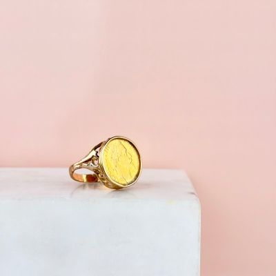 un gros plan d'une bague en pièce d'or posée sur un bloc de marbre