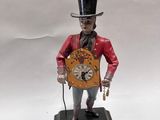 une figurine représentant un homme coiffé d'un haut-de-forme et tenant une horloge