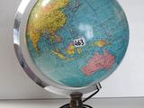 un globe terrestre posé sur un socle, sur une table