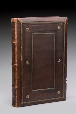 un livre ancien avec une couverture en cuir marron et des bordures dorées
