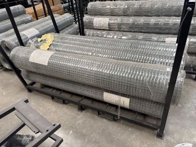 de nombreux rouleaux de treillis métallique sur une palette dans un entrepôt