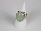 a close up of a ring with a green stone on a white cone