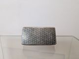 silver purse on a glass table with a white wall in the background