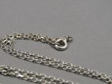 chaîne plaquée argent avec un fermoir, sur un fond gris