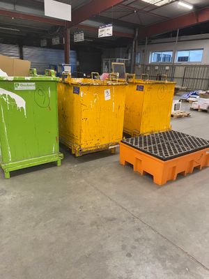 trois bacs jaunes et verts placés les uns à côté des autres dans un entrepôt