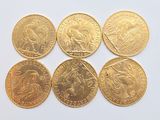 six types différents de pièces d'or posées sur une surface blanche