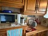 un micro-ondes posé sur un plan de travail dans une cuisine équipée d'armoires en bois