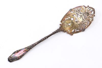une cuillère en argent avec un manche rose posée sur une surface blanche