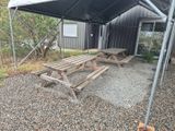 deux tables de pique-nique sous une tente, dans une aire en gravier