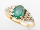 an oval emerald and diamond ring on a white background