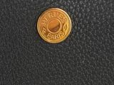 a close up of a black purse with a gold coin on it