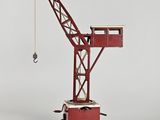 une petite grue rouge posée sur un chariot