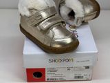 a small white cat sitting on top of a gold shoe
