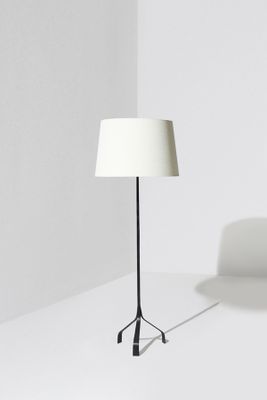 Le lampadaire est doté d'un pied noir et d'un abat-jour blanc.