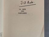 un livre ouvert, sur lequel figure une citation manuscrite, posé sur une table