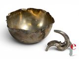 a silver bowl and a metal object on a white surface