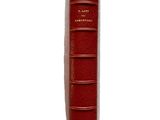 an old red book sitting on top of a table next to a white wall