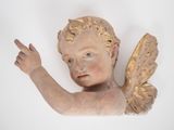 une statue représentant un ange qui montre quelque chose du doigt sur le mur