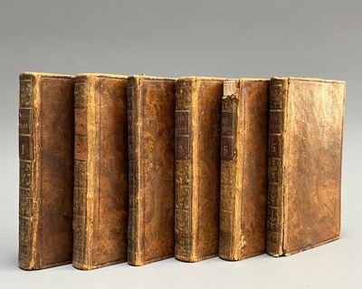 quatre vieux livres sont alignés les uns à côté des autres sur une surface grise