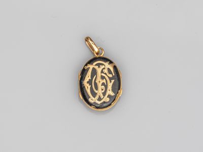 un pendentif plaqué or orné d'un monogramme en noir et blanc