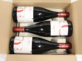 three bottles of red wine in a cardboard box on a table