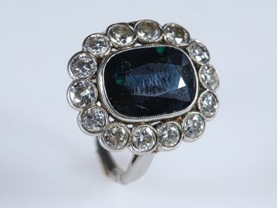 gros plan d'une bague avec une pierre bleue entourée de diamants