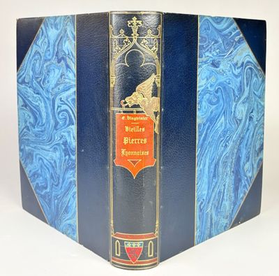 an old book with a blue cover sitting on a white surface