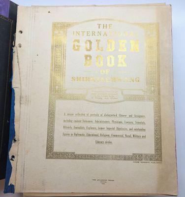 un livre ouvert, dont la couverture est ornée d'une dorure à chaud, posé sur une table