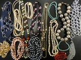 many different types of necklaces and bracelets laid out on a table