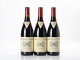 three bottles of red wine sitting on top of a white table