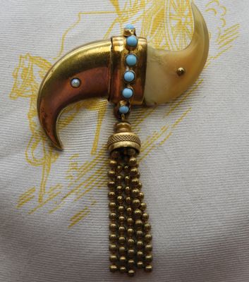 un gros plan sur un collier en or et turquoise orné d'une corne