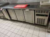 stainless steel counter top in a commercial kitchen with refrigerators and freezers