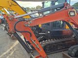 a small orange excavator that is parked in a lot