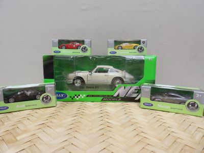 Quatre petites voitures sont posées sur une table, à côté de boîtes contenant d'autres petites voitures.