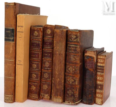 several old books are stacked on top of each other on a white surface