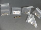 cinq pochettes de bijoux posées sur une table, accompagnées d'une étiquette nominative