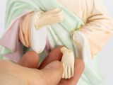 a hand holding a figurine of jesus holding a baby jesus