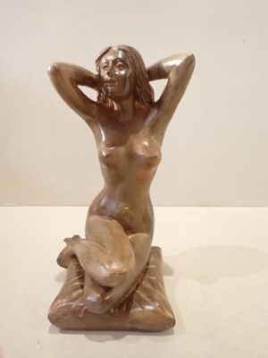 statue of a woman sitting on a rock with her hands behind her head