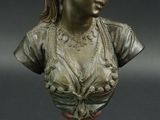 un petit buste en bronze représentant une femme, posé sur un socle en bois